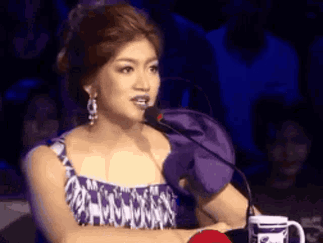 a woman speaking into a microphone with a cup in front of her that says ' i love you ' on it