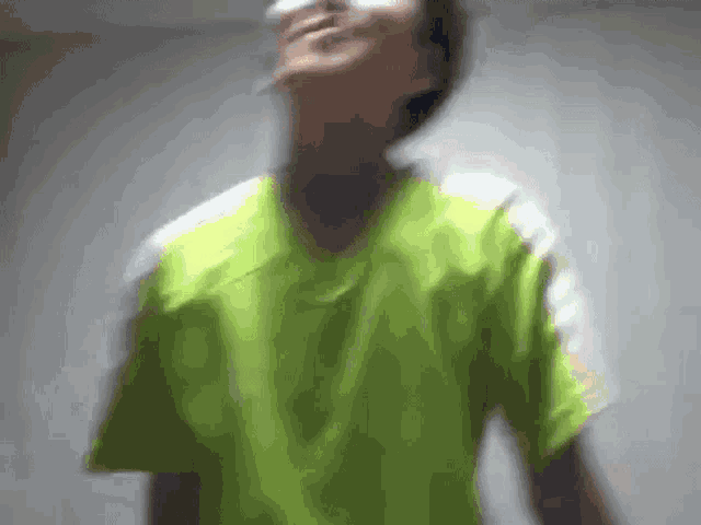 a blurry picture of a person wearing a green shirt and smoking a cigarette .