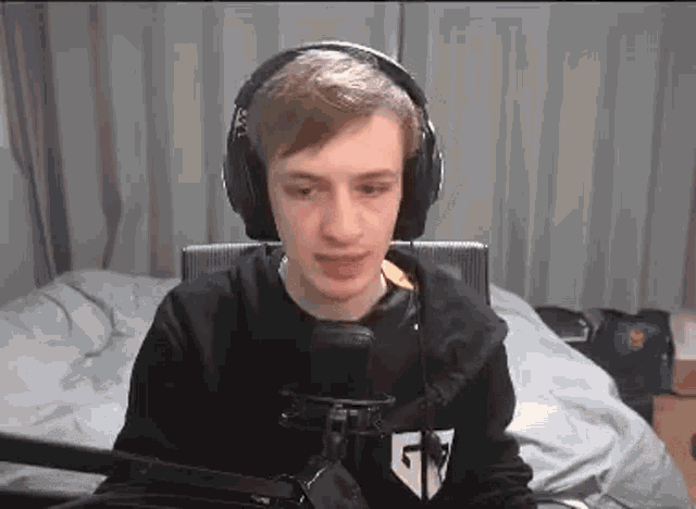 a man wearing headphones is sitting in front of a microphone .