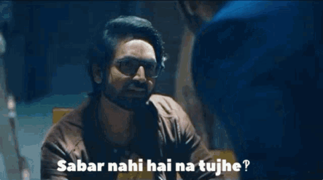a man with glasses is talking to another man with the words " sabar nahi hai na tujhe "