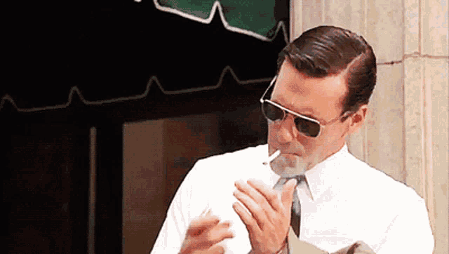 a man wearing sunglasses is smoking a cigarette outside