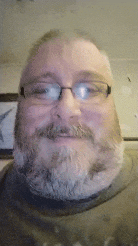 a man with glasses and a beard is smiling at the camera