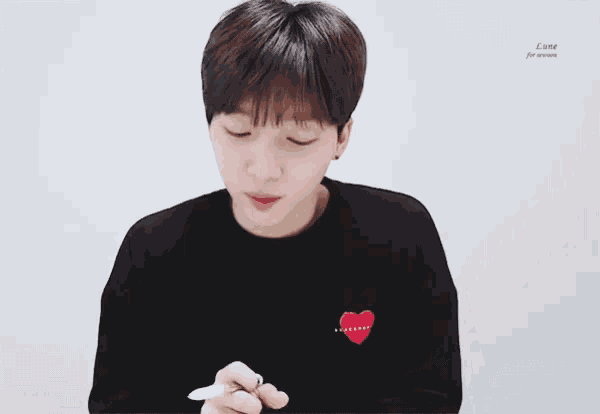 a young boy wearing a black sweater with a red heart on it