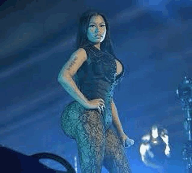 a woman is standing on a stage with her hands on her hips holding a microphone .