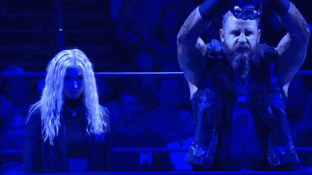 a man with a beard stands next to a woman in a dark room
