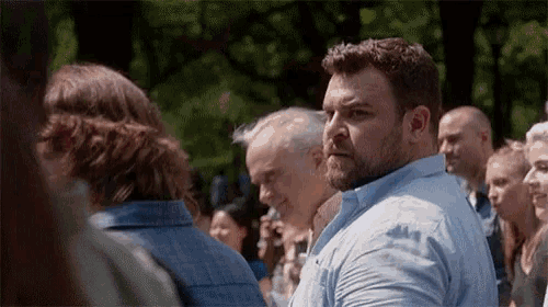 a man in a blue shirt stands in a crowd