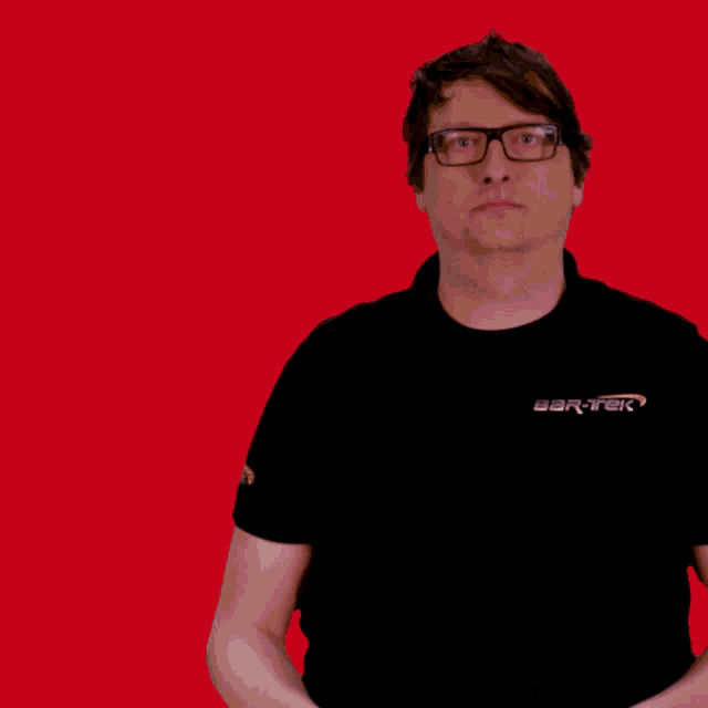 a man wearing glasses and a black shirt is holding a red object in front of his head