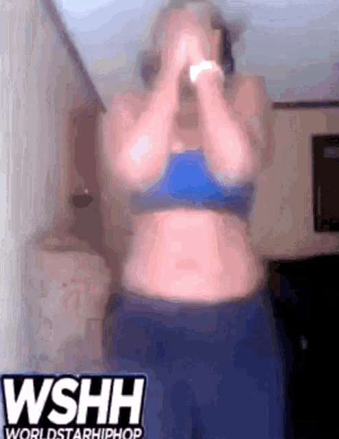 a woman in a blue top and blue shorts stands in front of a sign that says wshh