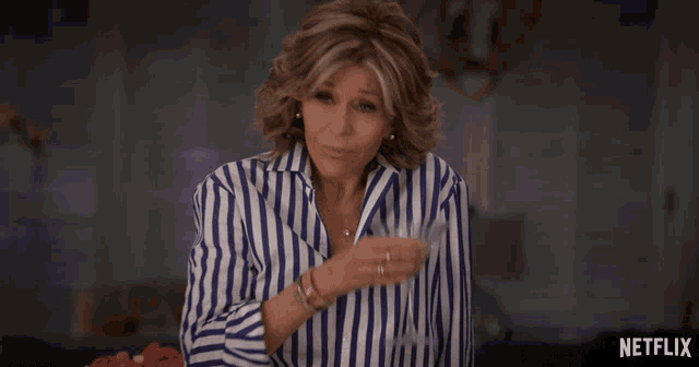 a woman in a blue and white striped shirt is sitting in front of a netflix sign