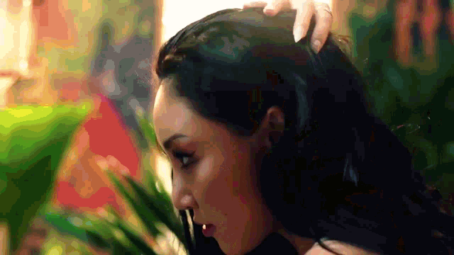 a close up of a woman 's head with a plant in the background .