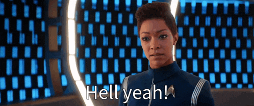 a woman in a space suit is standing in front of a wall and says hell yeah .