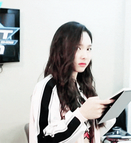 a girl with long hair is holding a tablet in front of a tv screen that says tk .