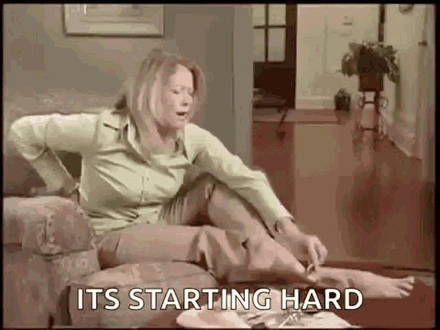 a woman is sitting on a couch with her legs crossed and a sign that says `` its starting hard '' .