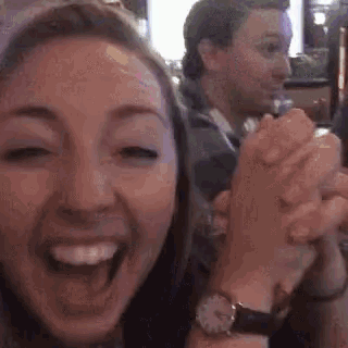 a woman is laughing while holding a man 's hand in front of her .