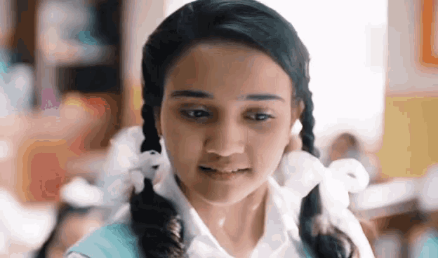 a girl with pigtails and a white bow in her hair looks at the camera