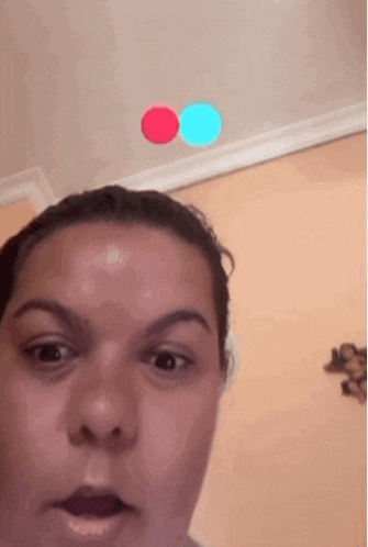 a woman is standing in front of a wall with two red and blue circles flying in the air .
