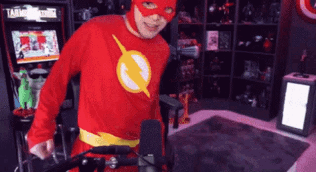 a man dressed in a flash costume is standing in front of a microphone
