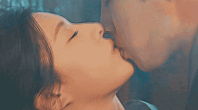a close up of a man and woman kissing each other .