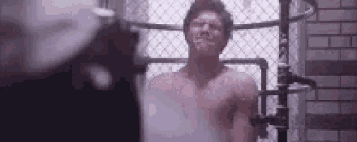 a shirtless man is taking a shower in a bathroom .