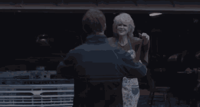 a woman is hugging a man in front of a blue truck
