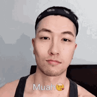 a young man with a bandana on his head is making a funny face .