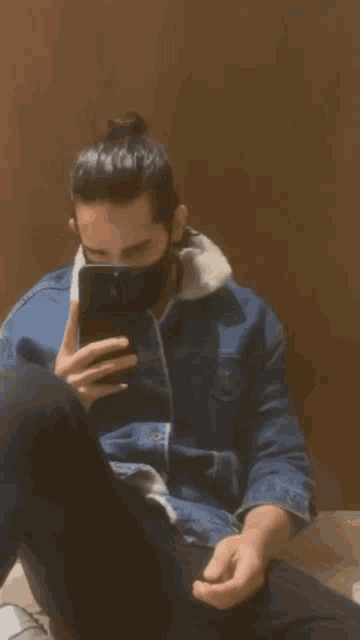 a man wearing a mask looks at his phone