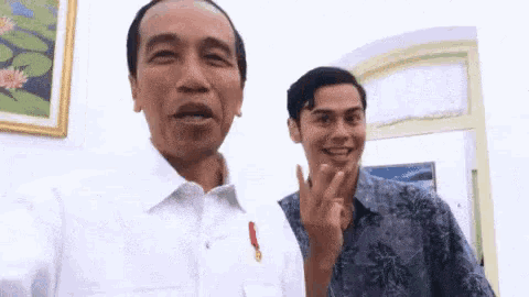 a man in a white shirt is standing next to a man in a blue shirt .