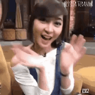 a woman with short hair is sitting on a couch with her arms outstretched and smiling .