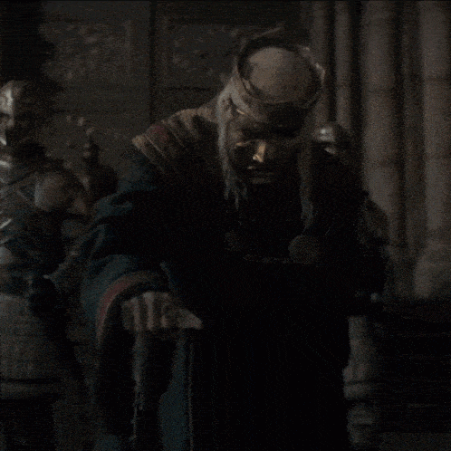 a man wearing a mask and a crown stands in front of a group of knights