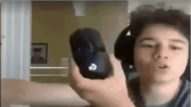 a young boy wearing headphones is holding a mouse in his hand .