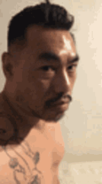 a man with a beard and a tattoo on his shoulder is looking at the camera .