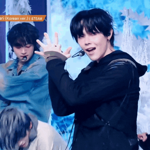 a group of young men are performing on a stage and one of them is wearing a hoodie