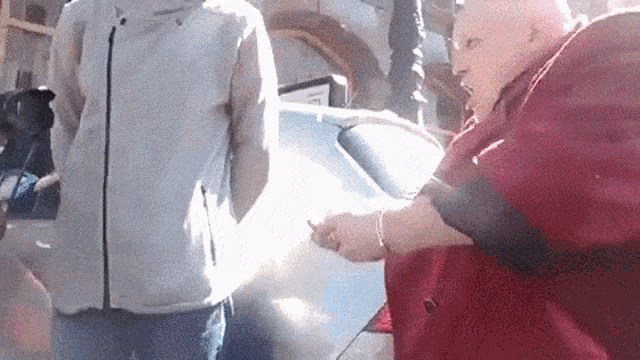 a man in a grey jacket is standing next to an older woman in a red coat