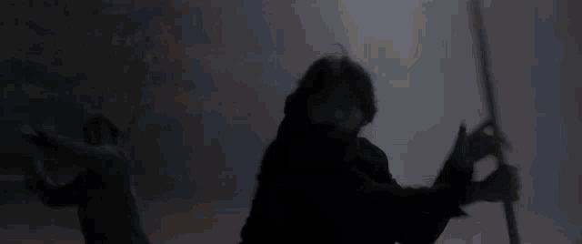 a man with a beard is holding a sword in a dark room