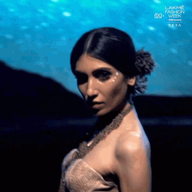 a woman stands in front of a sign that says lakme fashion week nexa