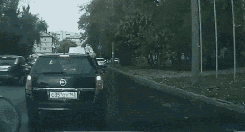 a man is riding a bike down a street next to a car with a license plate that says g357ov102