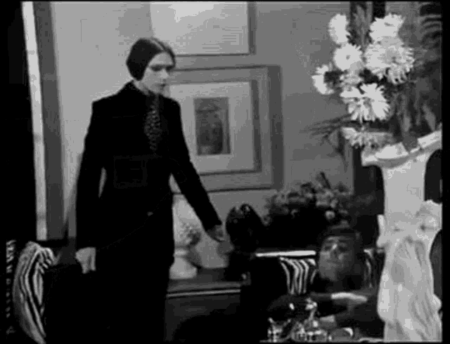 a black and white photo of a woman standing in a living room .