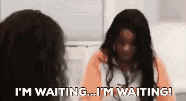 two women are sitting next to each other and one is saying i 'm waiting .