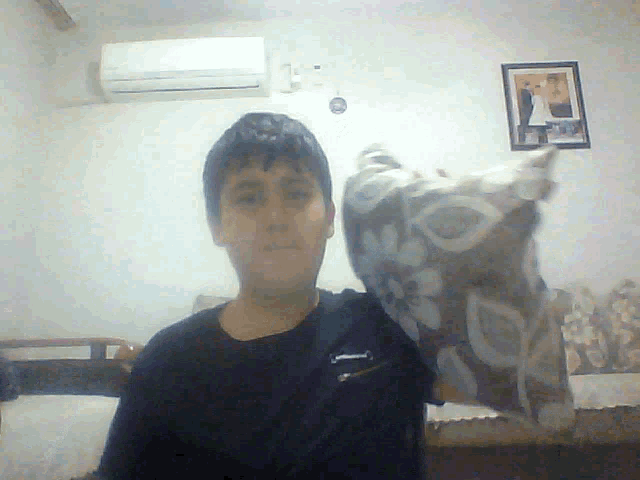 a boy in a black nike shirt holds a pillow in his hand