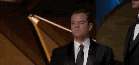 a man in a suit and tie is standing in front of a microphone on a stage .