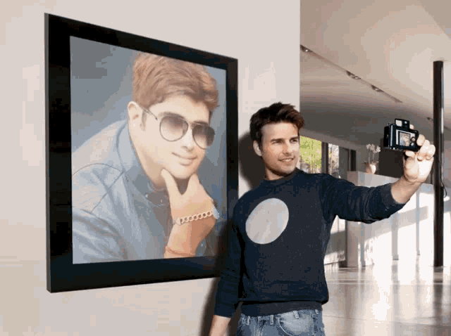 a man taking a selfie in front of a framed picture of a man