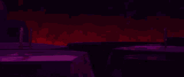 a group of people are standing in a dark room with red lights .