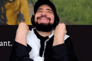 a man with a beard wearing headphones and a beanie is smiling with his arms in the air .