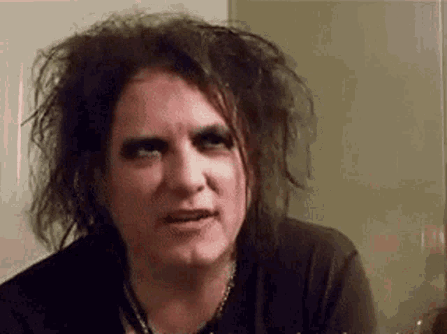 a man with a nose ring and a black shirt is making a funny face with his eyes closed .