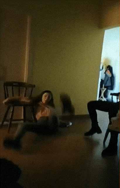 a girl in a pink sweater is dancing in a living room