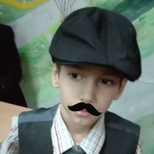 a boy wearing a hat and a fake mustache on his face