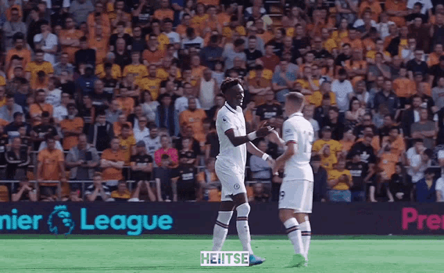 two soccer players shake hands in front of a league banner