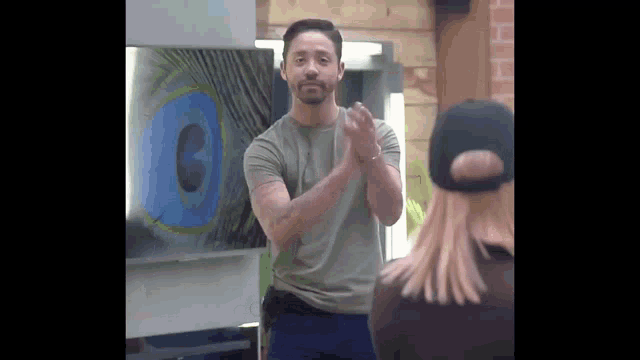 a man is clapping his hands in front of a peacock feather painting .
