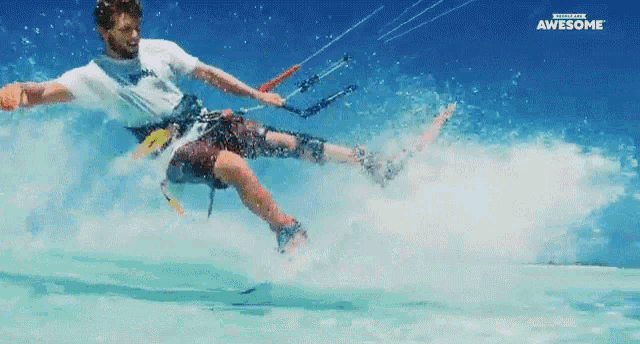 a man in a white shirt is flying a kite in the ocean with the word awesome behind him