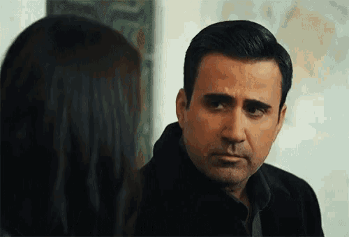 a man and a woman are looking at each other . the man is wearing a black jacket .
